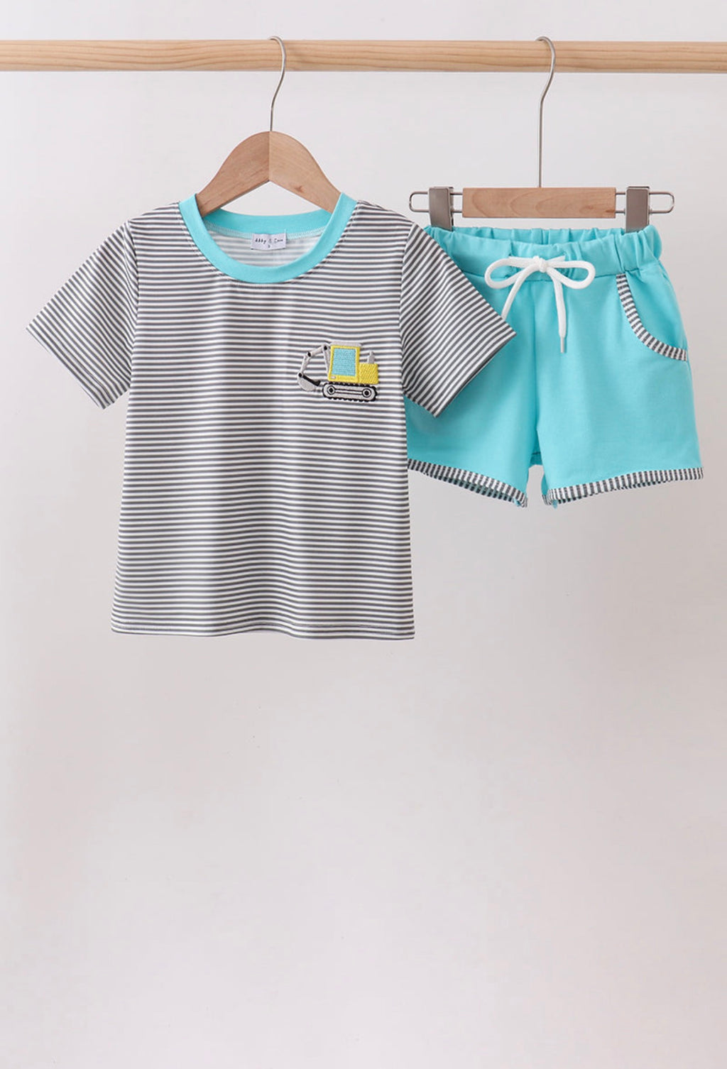 Children's outfit with striped shirt and blue shorts on hangers against a white background
