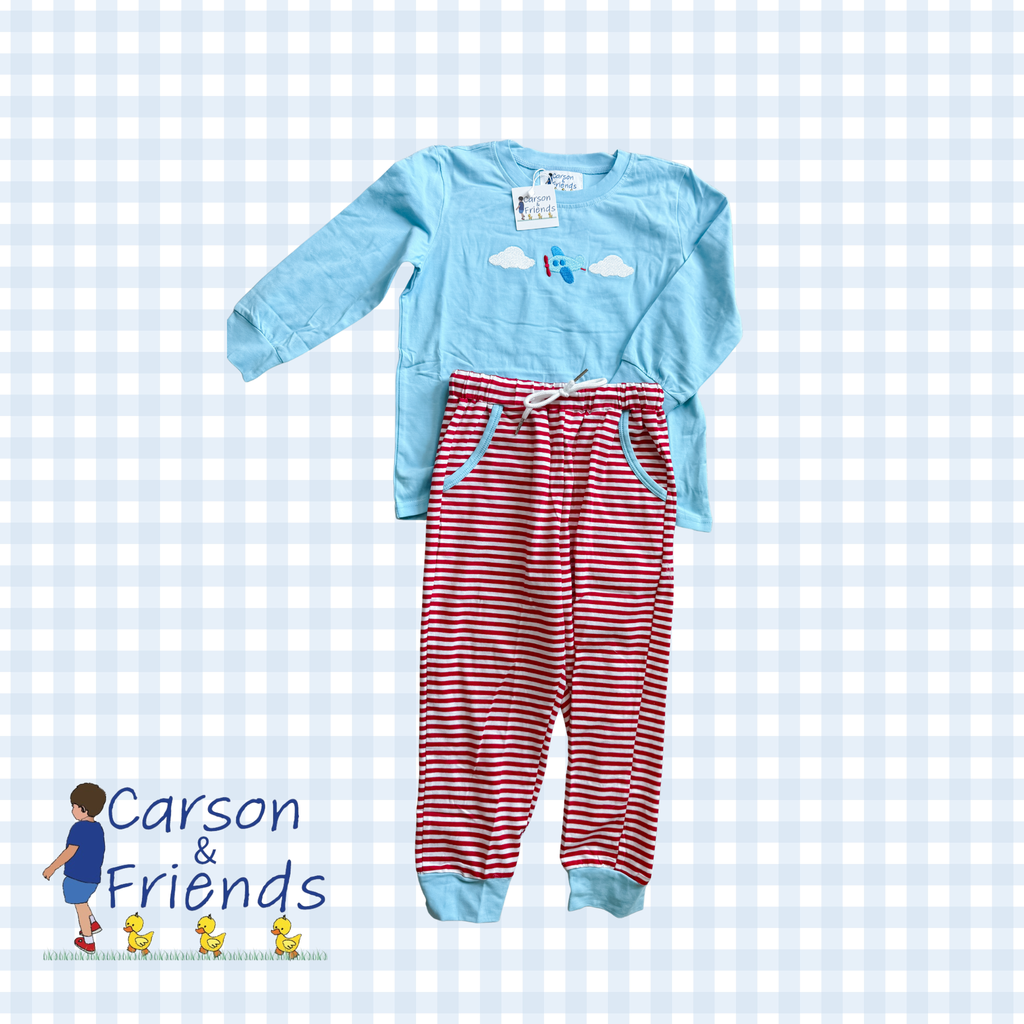 light blue long-sleeve pajama top with a small airplane and clouds graphic, paired with red and white striped pajama pants with a white drawstring.