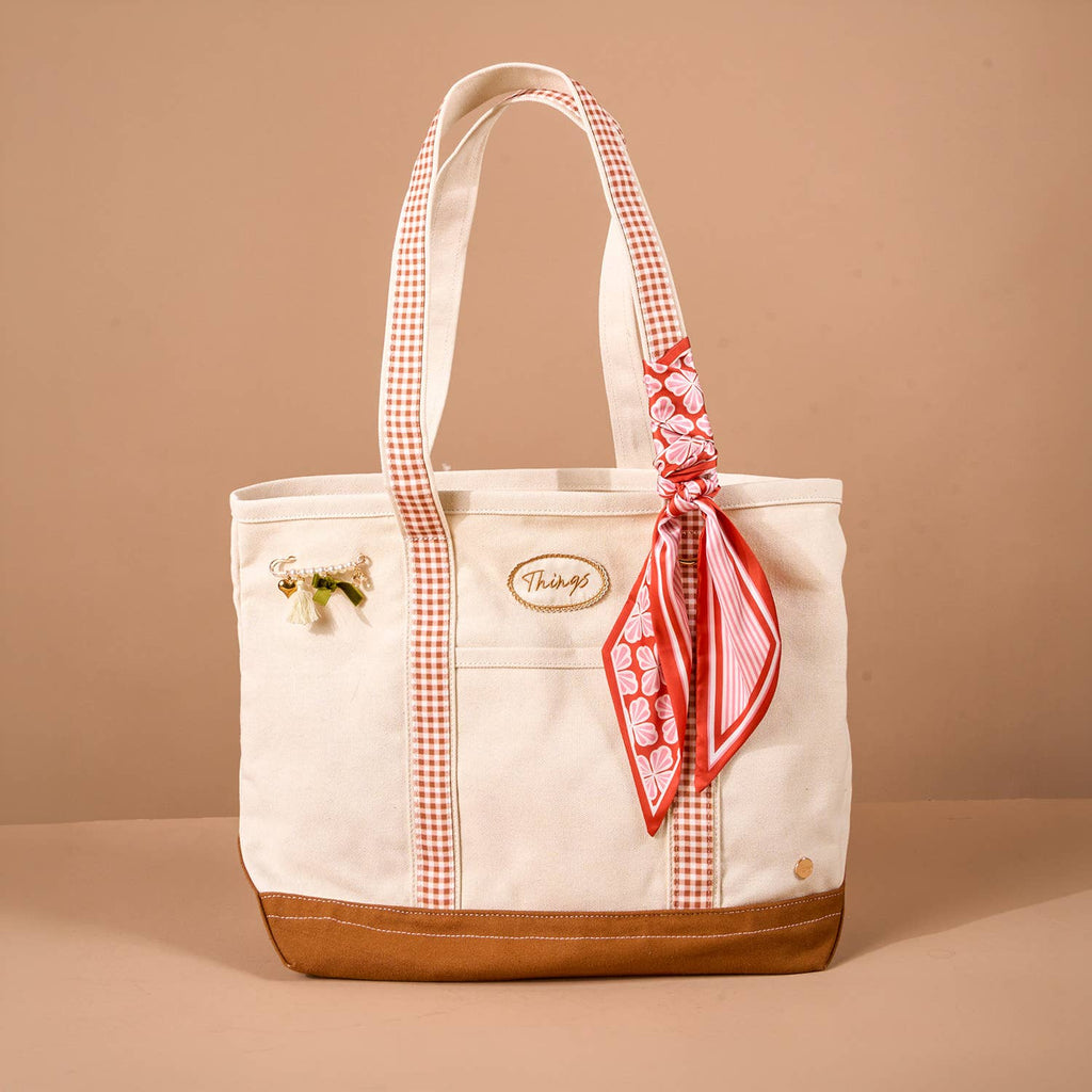 White tote bag with maple checkered handles and a matching scarf on a beige background