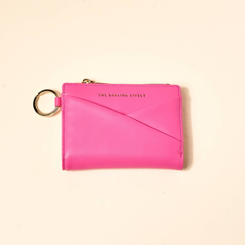 Pink wallet with keychain on a beige background